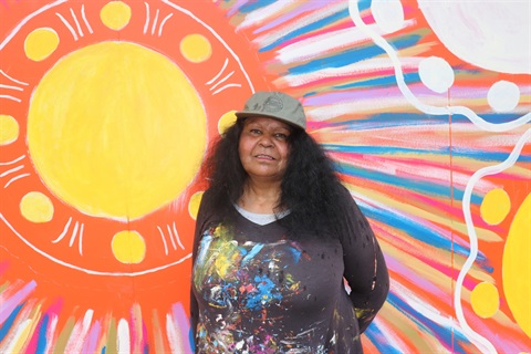 Artist Fiona Clarke stands beside her mural at the Diamond Valley Sports and Fitness Centre