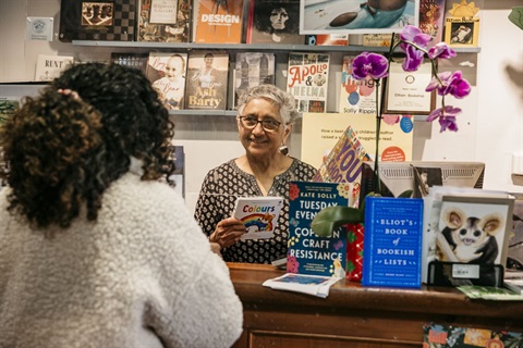 A bookstore cashier smiling at a customer while serving them from the counter