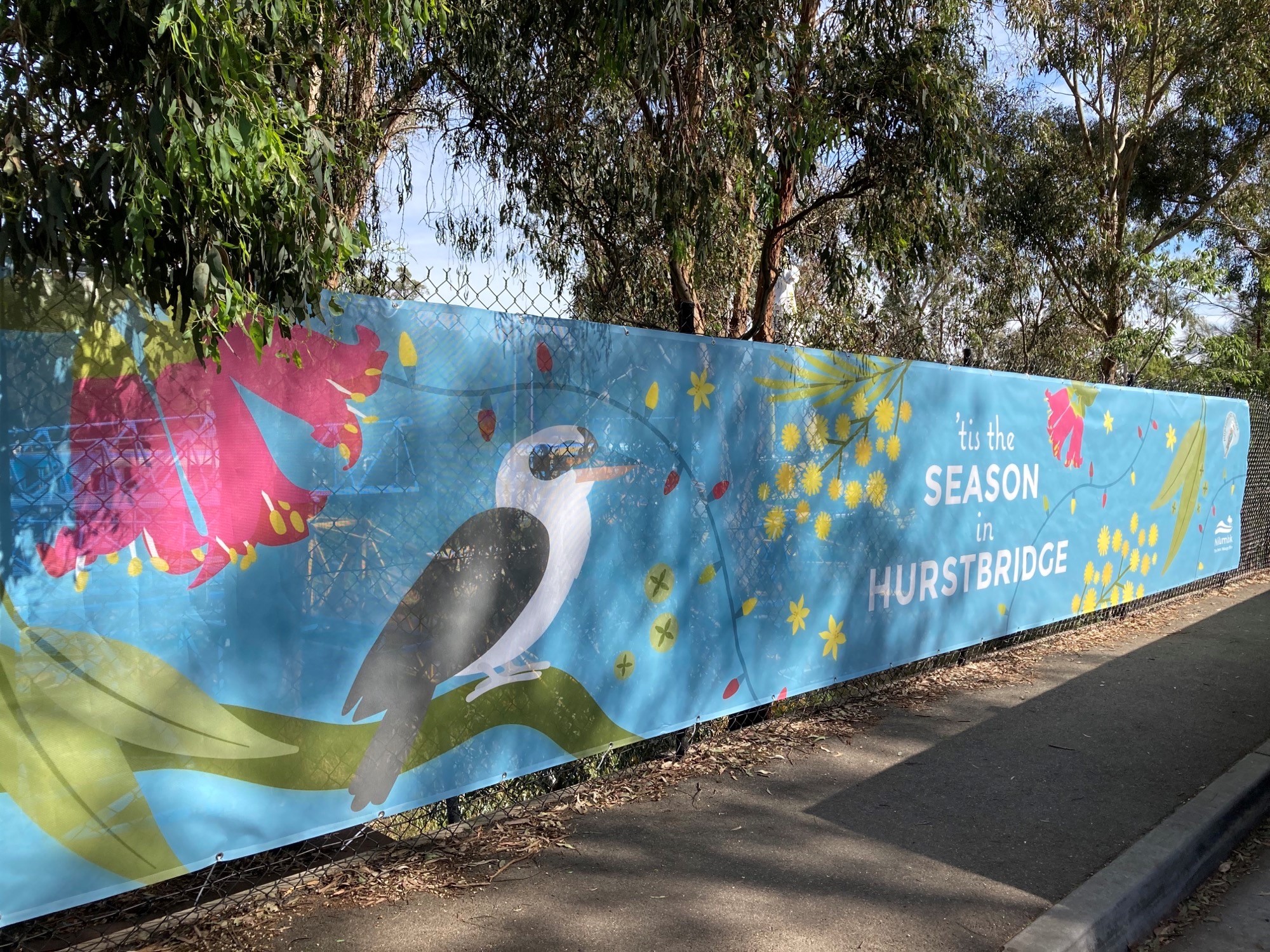 Photo of a fence covered in a promotional banner that reads 