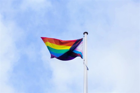 This is an image of the LGBTIQA+ flag flying in the wind