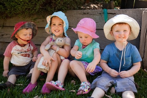 Photo of four young children sitting on the grass