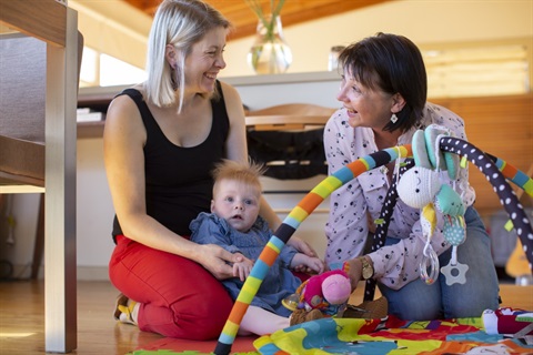 Photo of two women playing with a baby