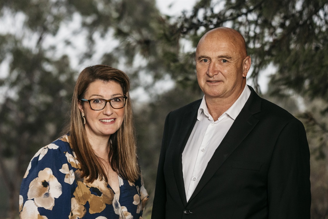 Professionally dressed woman and man pose in an outdoor setting