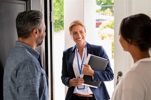 Man and woman open door to a woman with paperwork to conduct a survey