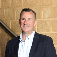 Photo of Nillumbik CEO Carl Cowie. Carl is wearing a suit and tie and standing in the foyer of the Nillumbik Council building.