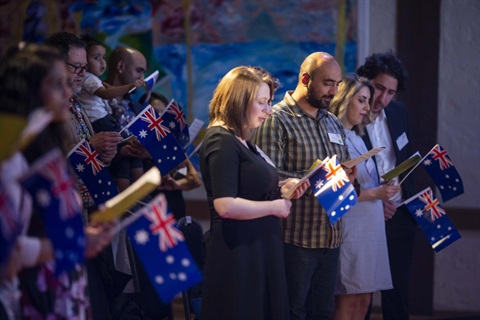 Photo of people standing in a group holding small Australian flags