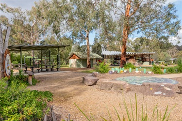 A playground featuring a labyrinth on the ground and structures in the background filled with playground equipment and tables and chairs