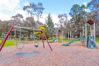 Swings and two slides sit in a spacious play area.