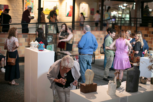 DiversARTy Opening 2023 Artworks including ceramics and paintings surrounded by a crowd of people