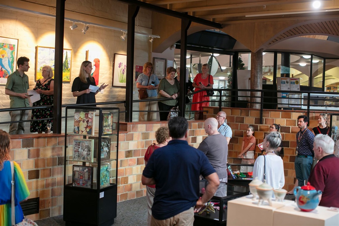 Guests gather in the Eltham library gallery to hear a woman present a speech at the diversARTy launch