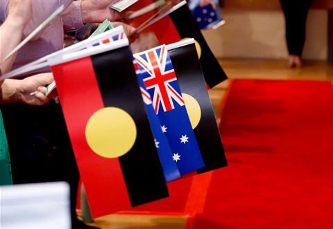 This is a photograph of people holding the Aboriginal and Australian flags at a Nillumbik citizenship ceremony.