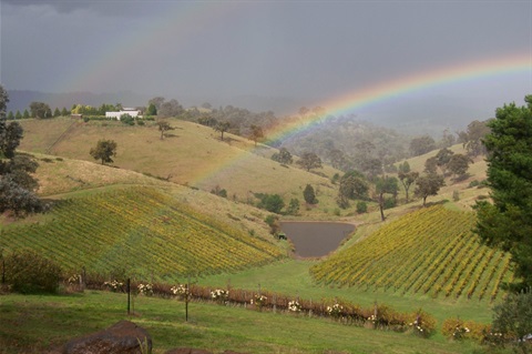 This is a photograph of a rainbow in the rural landscape.