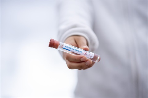 Photo of a person's hand holding a vial of vaccine