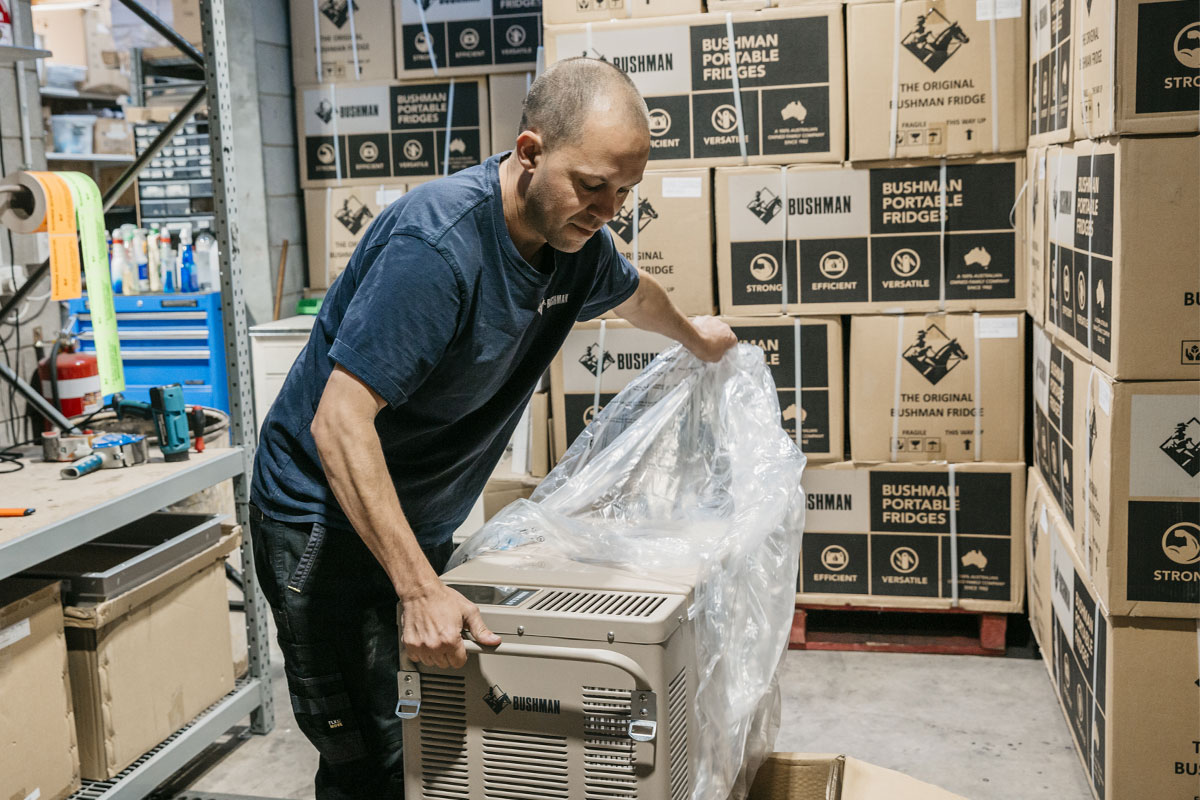 A man is in a warehouse taking plastic off equipment