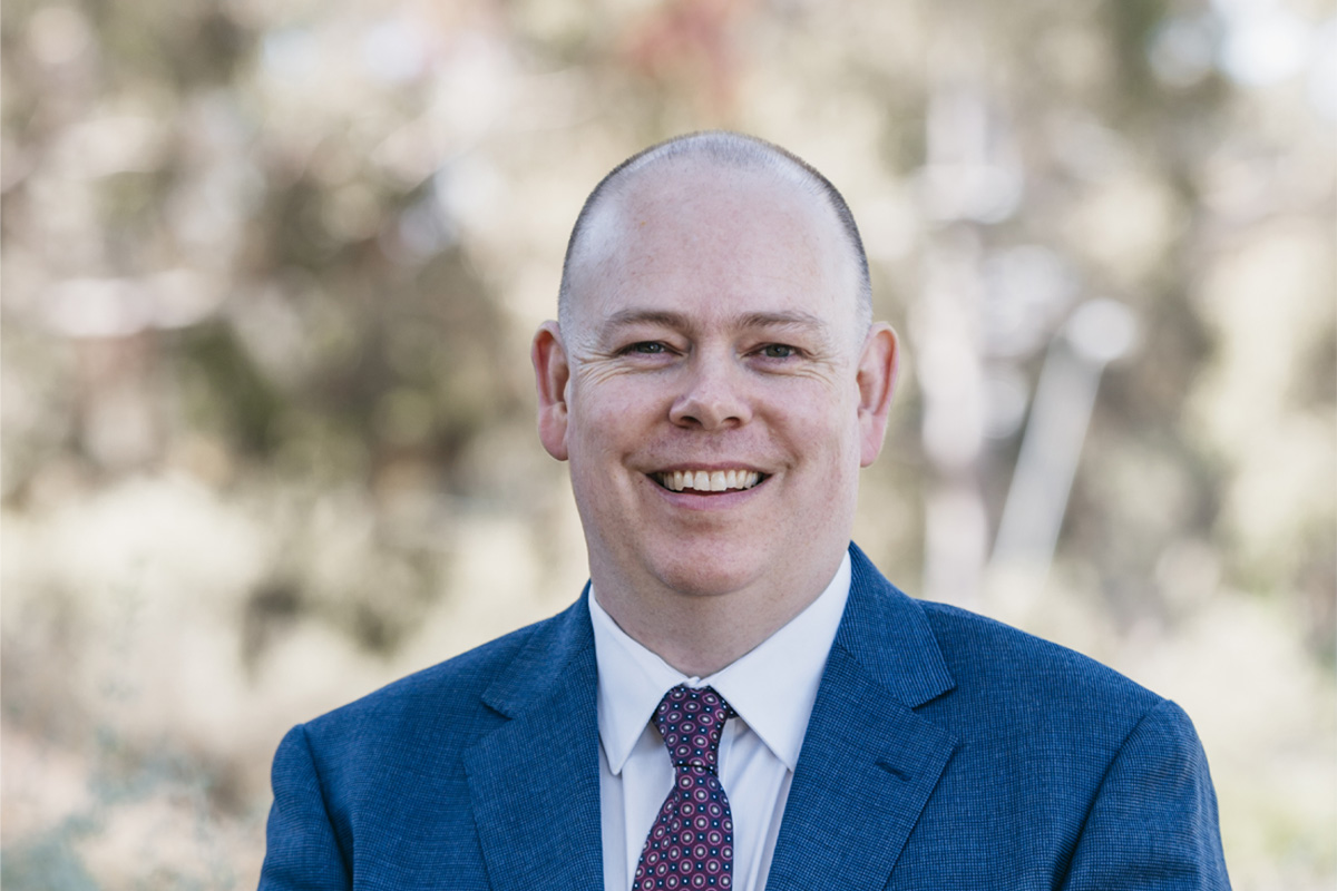 Photo of Jeremy Livingston. Jeremy is wearing a suit and tie and standing in the foyer of the Nillumbik Council building.