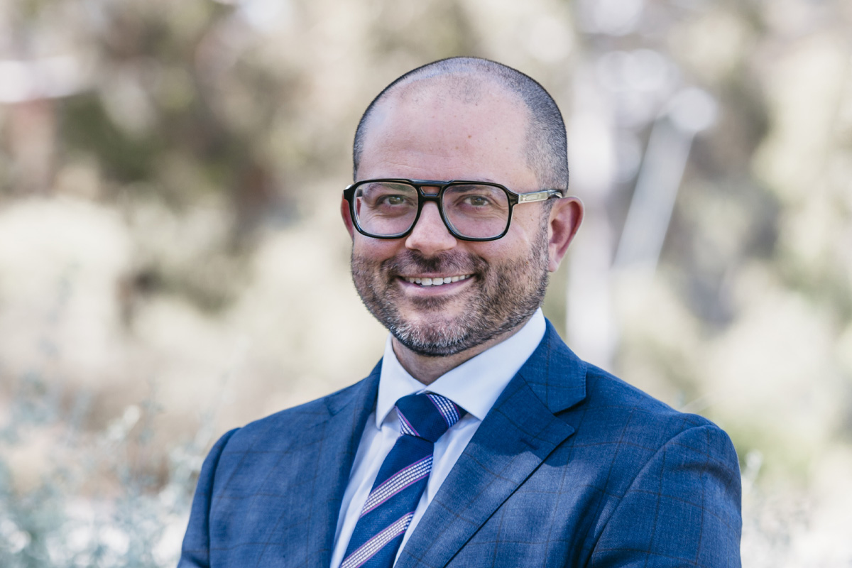 Photo of Vincenzo Lombardi. Vincenzo is wearing a suit and tie and standing in the foyer of the Nillumbik Council building.